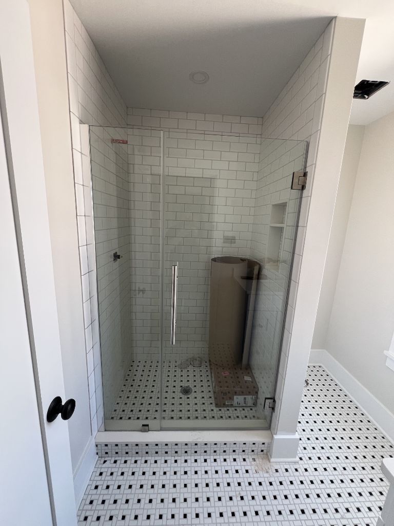 Frameless glass shower enclosure with white subway tile