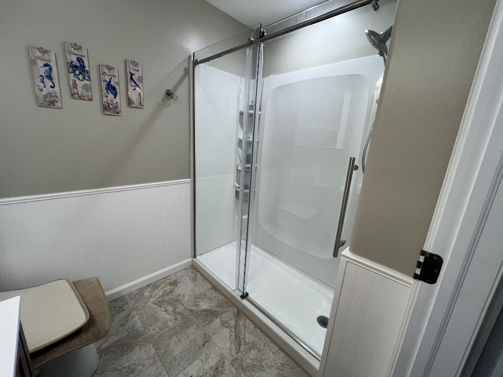 Sliding glass shower door in coastal bathroom