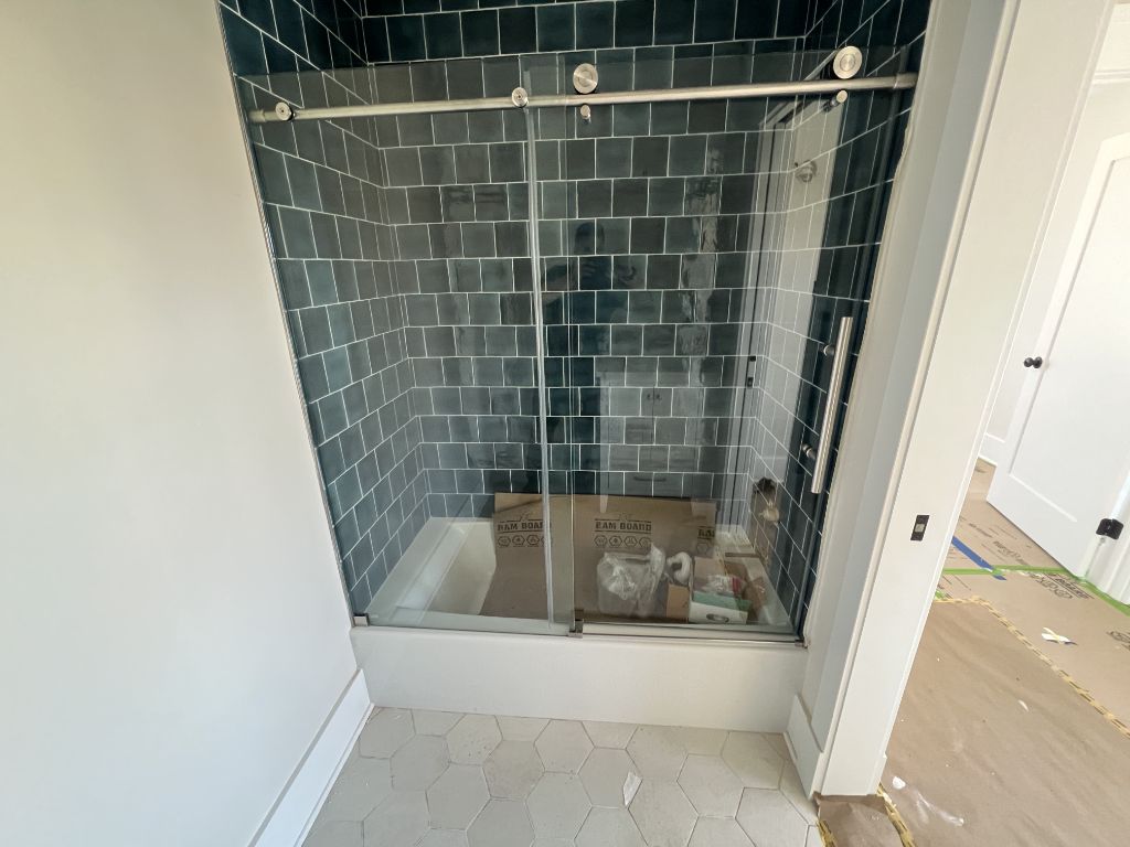 Sliding glass shower door with blue subway tile